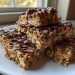 A stack of homemade 5-ingredient protein bars made with oats and drizzled generously with melted chocolate.