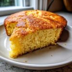 A close-up of a thick, golden slice of amazing 1 skillet cornbread resting on a light plate.