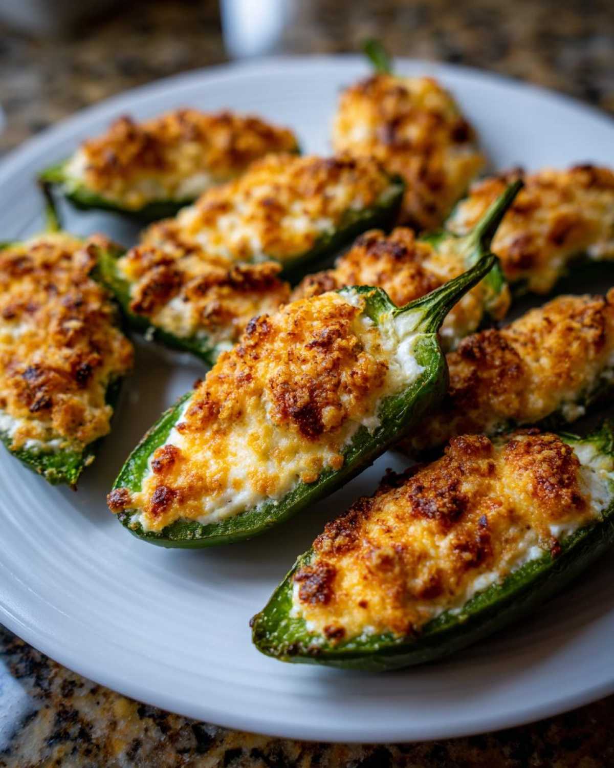 A plate of freshly baked Jalapeño poppers stuffed with creamy filling and topped with a golden, crispy breadcrumb crust.