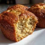 Close-up of a banana protein muffin with a bite taken out, showing the moist, textured interior.