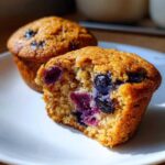 Close-up of a homemade blueberry protein muffin cut in half showing moist interior and burst blueberries.