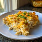 A generous serving of cheesy chicken and rice casserole topped with melted cheddar and green onions.