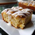 Close-up of a moist slice of cinnamon roll casserole drizzled generously with white vanilla icing.