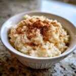 Close-up of creamy rice pudding served in a white bowl and generously dusted with cinnamon.