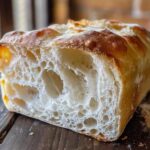Close-up of the open crumb structure of a freshly baked Italian bread loaf, showing large air pockets.