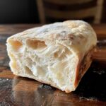 Close-up of the airy, open crumb structure inside a slice of crusty Italian bread.