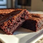 Close-up of two rich, fudgy sweet potato brownies cut into squares, resting on a white plate.