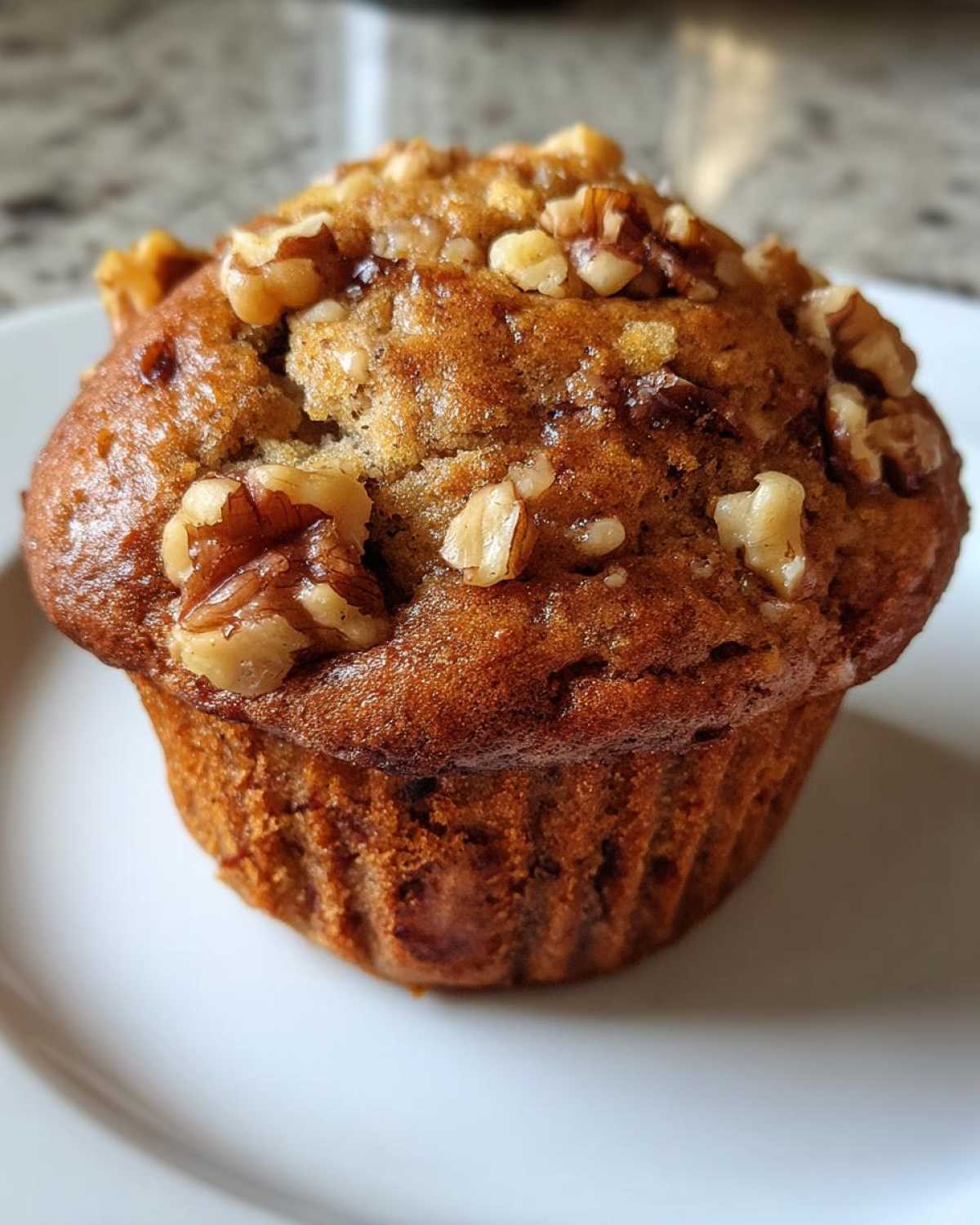 Close-up of a perfectly baked banana nut muffin, featuring a golden-brown top studded with crunchy walnuts.