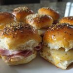 A plate of warm Ham and Cheese Sliders featuring melted cheese and poppy seed topping.