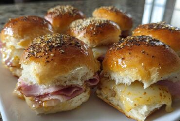 A plate of warm Ham and Cheese Sliders featuring melted cheese and poppy seed topping.