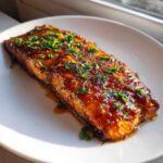 A perfectly cooked fillet of salmon glazed with honey garlic butter and topped with fresh parsley.