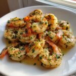 Close-up of juicy air fryer shrimp seasoned with garlic and fresh parsley, resting in butter sauce.