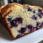 Close-up of a thick slice of moist blueberry banana bread showing tender crumb and juicy blueberries.