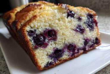 Close-up of a thick slice of moist blueberry banana bread showing tender crumb and juicy blueberries.
