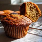 Close-up of a perfectly baked, moist honey bran muffin with a halved muffin showing the texture behind it.