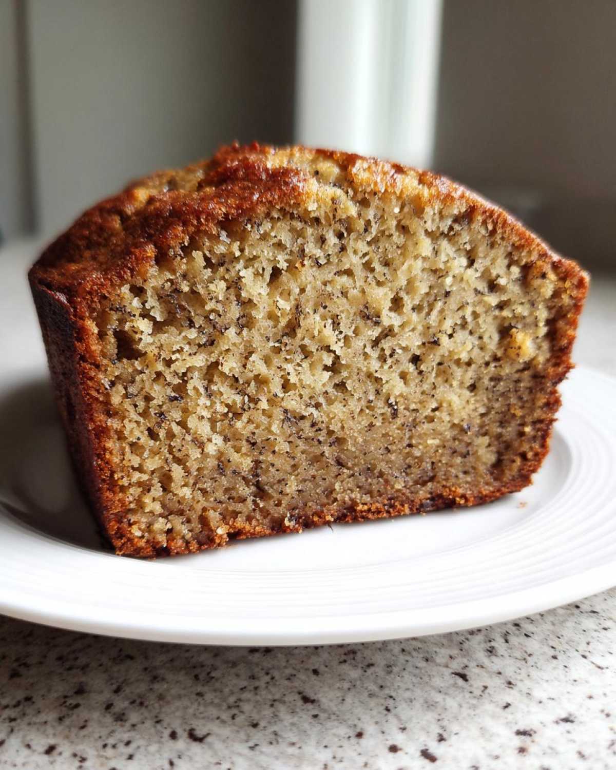 Close-up of a moist slice of sugar free banana bread showing its tender crumb and dark banana flecks.