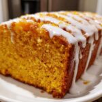 Close-up of a moist sweet potato pound cake loaf with thick white glaze drizzled across the top.