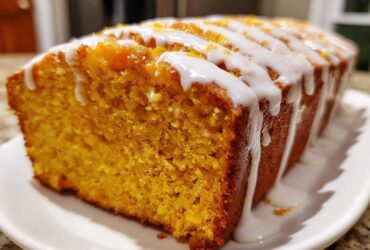 Close-up of a moist sweet potato pound cake loaf with thick white glaze drizzled across the top.