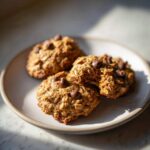 Close-up of four oatmeal chocolate chip breakfast cookie treats arranged on a light ceramic plate.