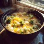 Close-up of steaming hot one-pot cheesy broccoli rice topped with melted cheddar cheese.