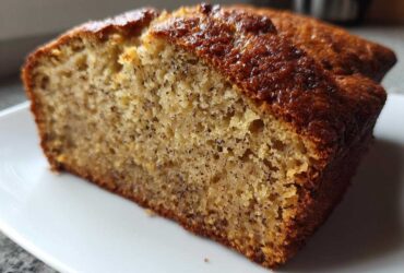 Close-up of a thick slice of moist sugar free banana bread showing its dense, speckled crumb and golden-brown crust.