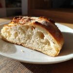 Cross-section of a crusty loaf made with sourdough discard pizza dough, showing an open, airy crumb structure.