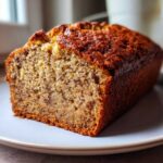 Close-up of a freshly baked slice of sugar free banana bread showing its moist crumb and dark crust.