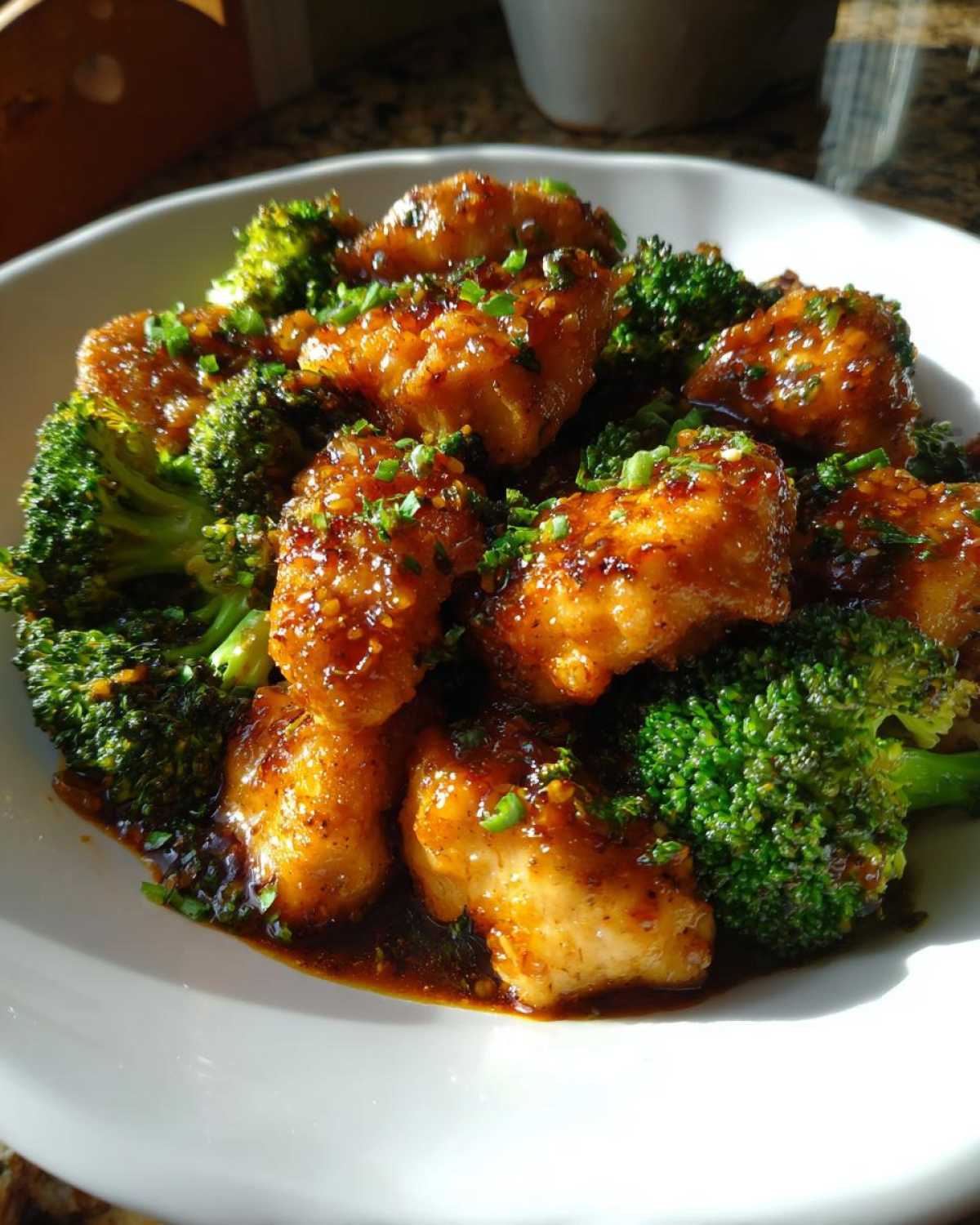 Close-up of glazed chicken pieces mixed with bright green broccoli florets, a perfect example of chicken and broccoli.