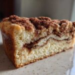 A thick slice of moist coffee cake showing a rich cinnamon swirl and generous crumbly streusel topping.