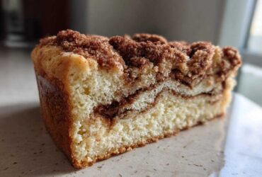 A thick slice of moist coffee cake showing a rich cinnamon swirl and generous crumbly streusel topping.
