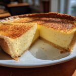 A perfect slice removed from a golden brown egg custard tart with a beautifully caramelized top.