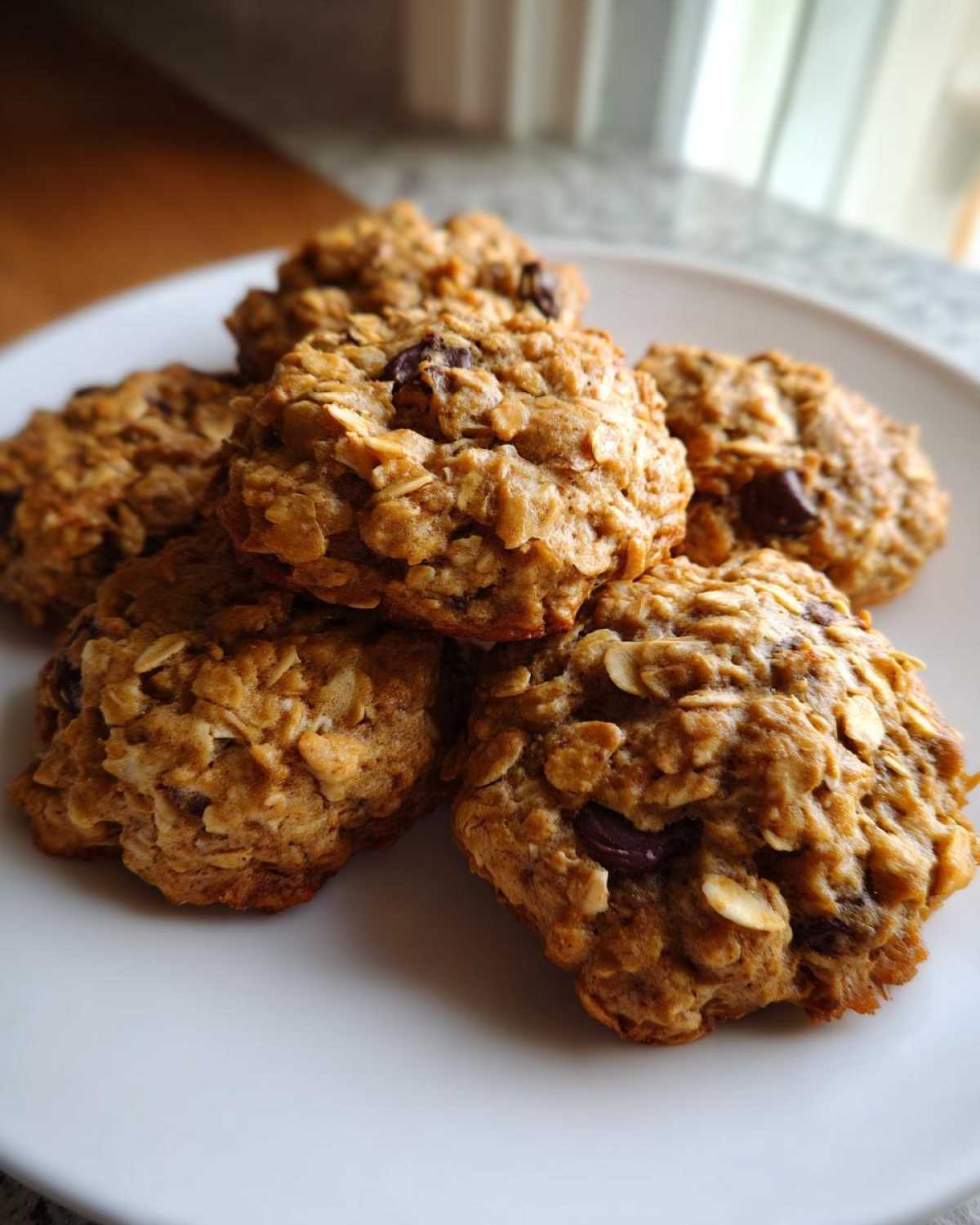 A stack of freshly baked, chewy oatmeal cookie treats with visible chocolate chips on a white plate.