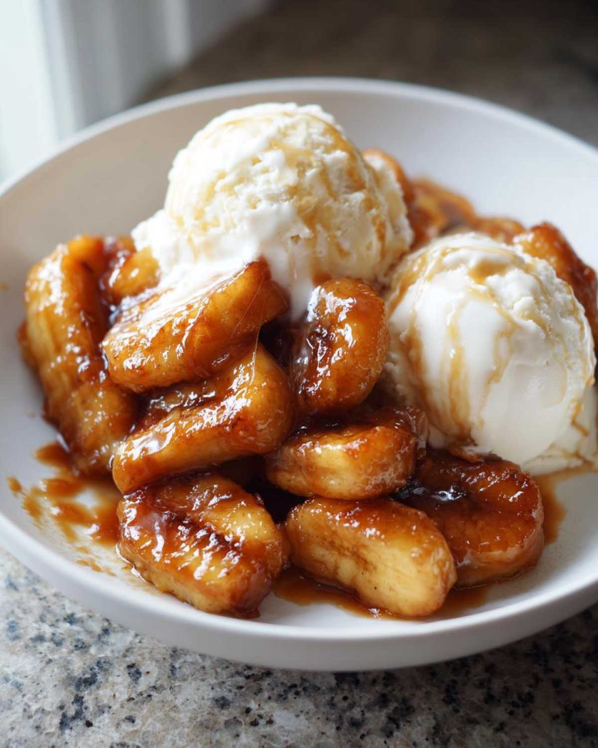 Close-up of warm, caramelized Bananas Foster served with two scoops of melting vanilla ice cream.