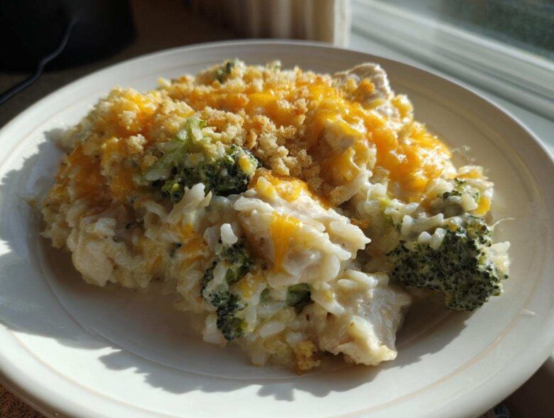 A close-up serving of creamy chicken broccoli rice casserole topped with melted cheddar cheese and breadcrumbs.