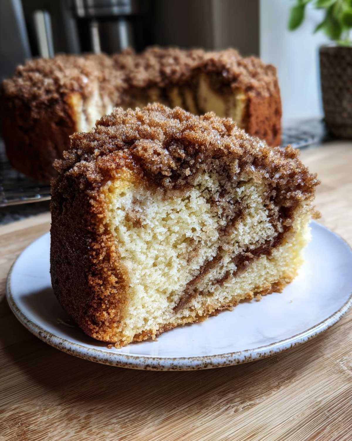 A thick slice of moist coffee cake with a generous cinnamon streusel topping, showing a swirl inside.