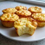 A plate of freshly baked cottage cheese egg cups starbucks style, with one cup having a bite taken out.