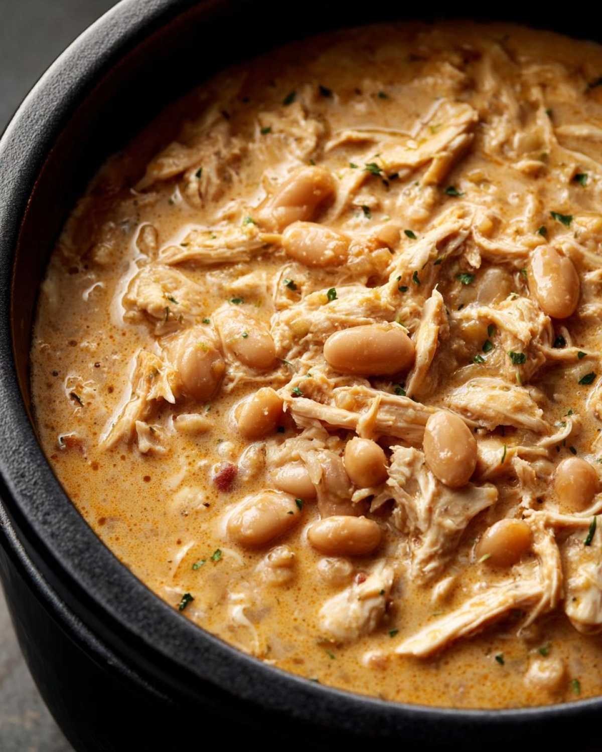 Close-up of creamy crockpot white chicken chili with shredded chicken and white beans.
