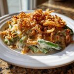 A close-up serving of creamy green bean casserole topped generously with crispy fried onions.