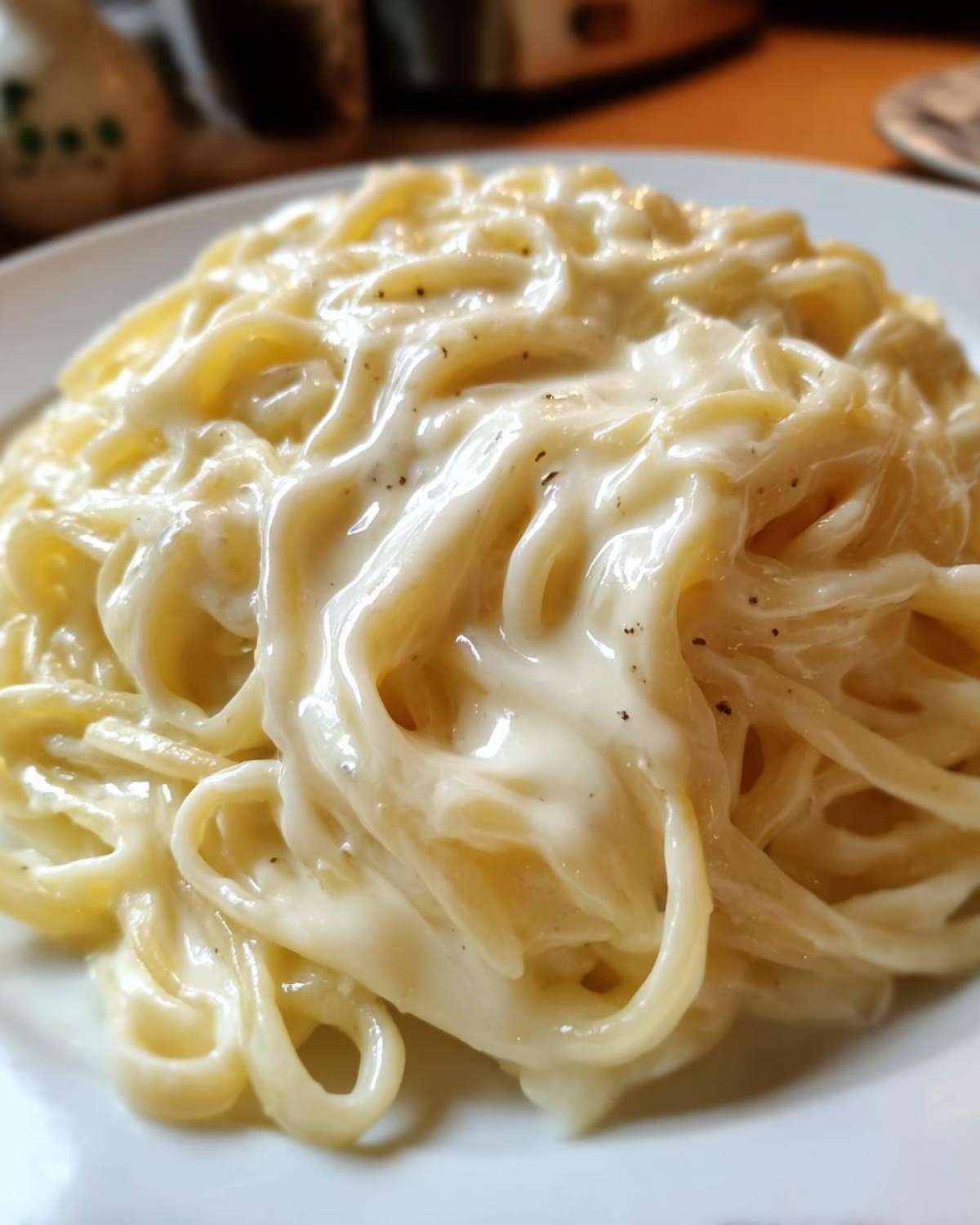 Close-up of fettuccine pasta generously coated in rich, creamy olive garden alfredo sauce, lightly seasoned with pepper.
