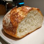 Close-up of a freshly baked Italian bread loaf cut in half, showing the airy interior crumb and golden crust.