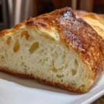 Close-up of a freshly baked Italian bread loaf, showing a golden-brown, crusty exterior and an open, airy crumb structure.