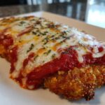 Close-up of a baked, breaded cutlet topped with marinara sauce and melted mozzarella for easy chicken Parmesan.