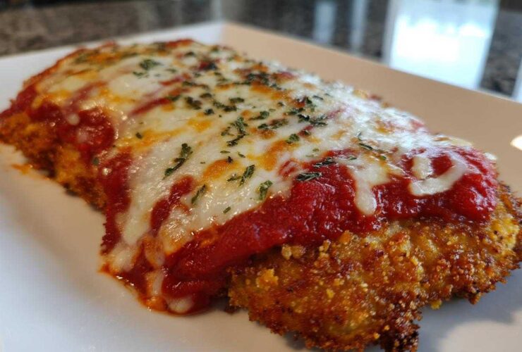 Close-up of a baked, breaded cutlet topped with marinara sauce and melted mozzarella for easy chicken Parmesan.