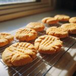 Freshly baked Easy Peanut Butter Cookies cooling on a wire rack in natural sunlight.