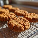 Close-up of several freshly baked Easy Peanut Butter Cookies cooling on a wire rack in natural sunlight.