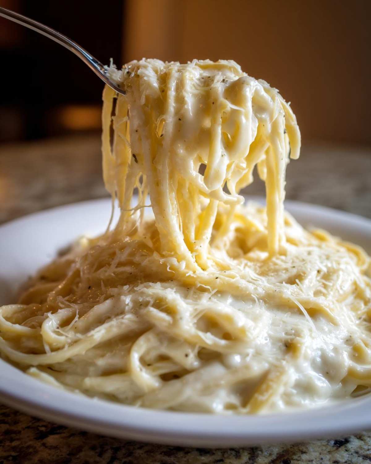 A fork lifting creamy fettuccine pasta coated heavily in rich Olive Garden Alfredo sauce and grated cheese.