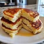 Cross-section view showing the incredibly fluffy texture of the amazing fluffy pancakes stacked on a white plate with syrup.