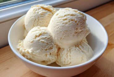 Four generous scoops of creamy, vanilla-colored protein ice cream served in a white bowl.