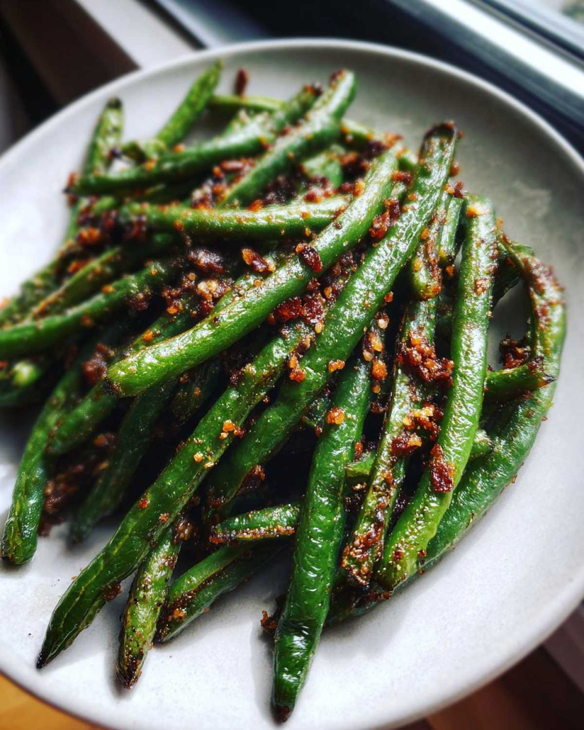Close-up of vibrant green beans tossed with crispy garlic bits, ready to serve.