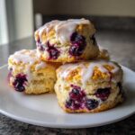 Close-up of three fluffy blueberry scones stacked, topped with a sweet white glaze.